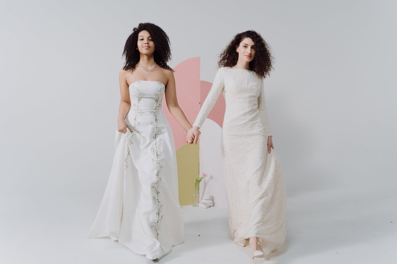 two women in wedding dresses holding hands