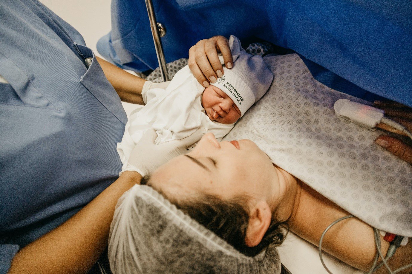 a newborn baby with their mother and a nurse