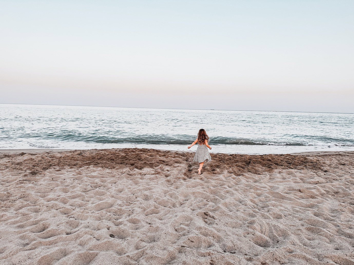 A young girl on the beach running towards the sea