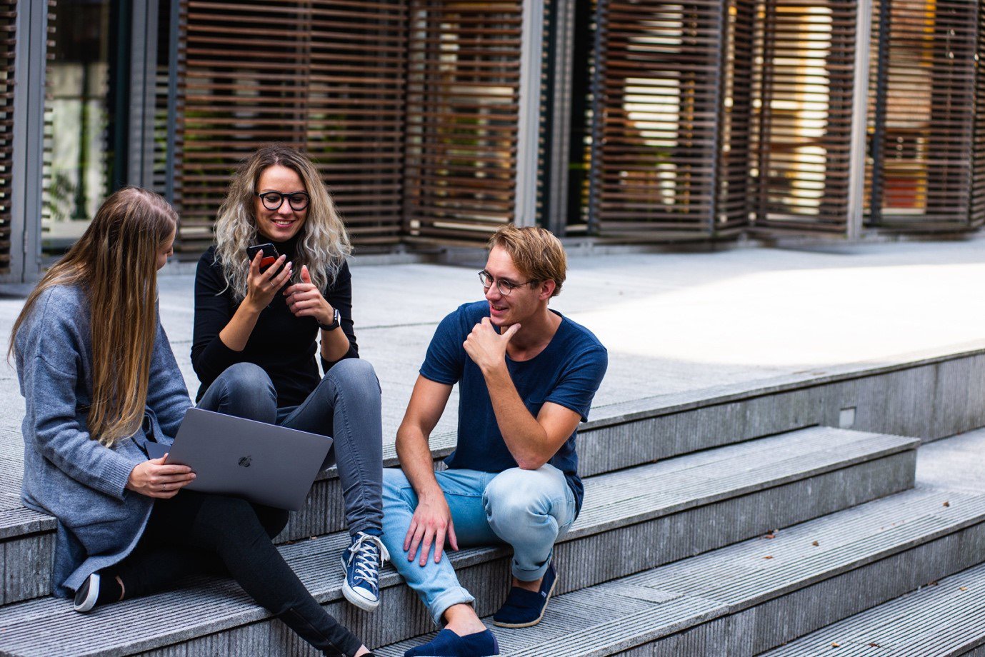 Older students sat on school steps with a laptop