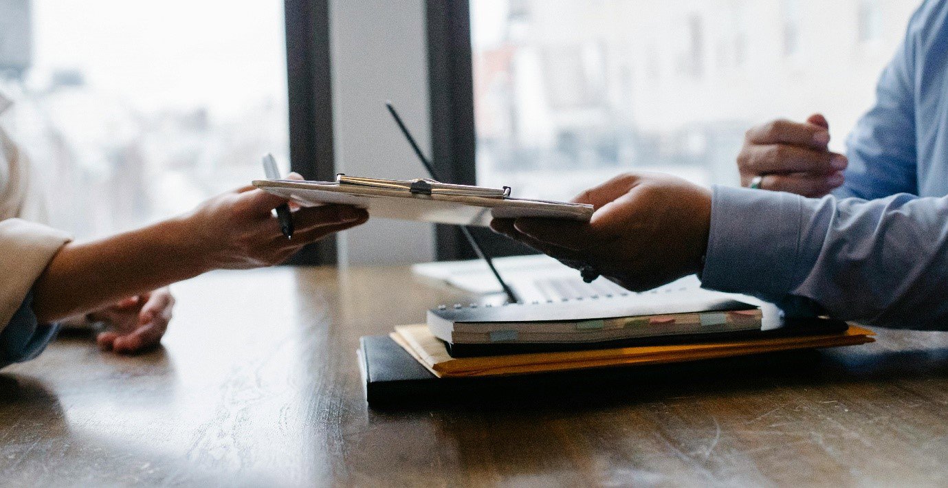 two people passing a clipboard between them