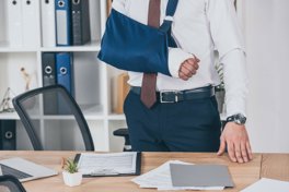 An office worker wearing a sling on his right arm