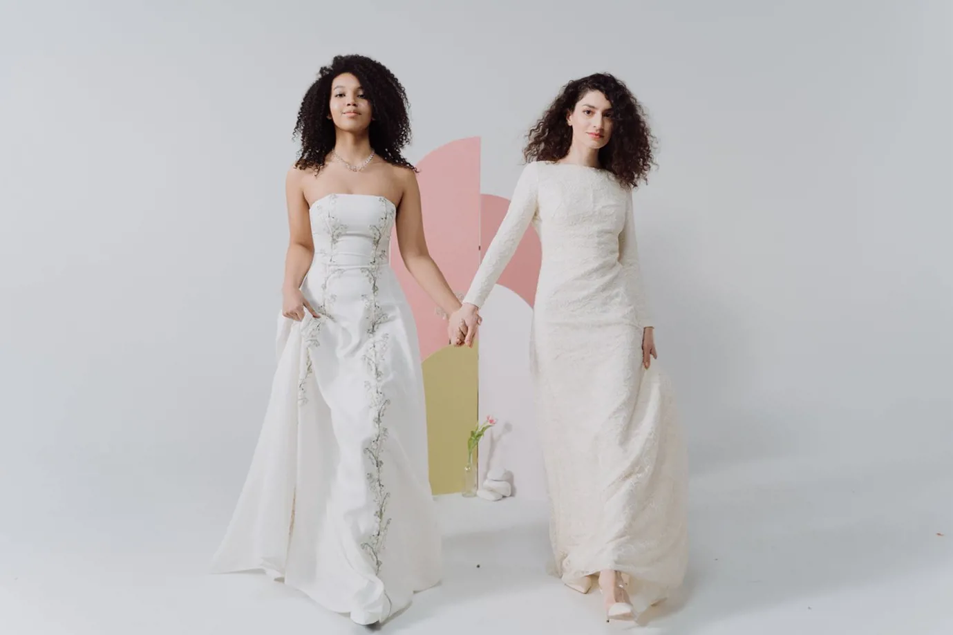 two women in wedding dresses holding hands