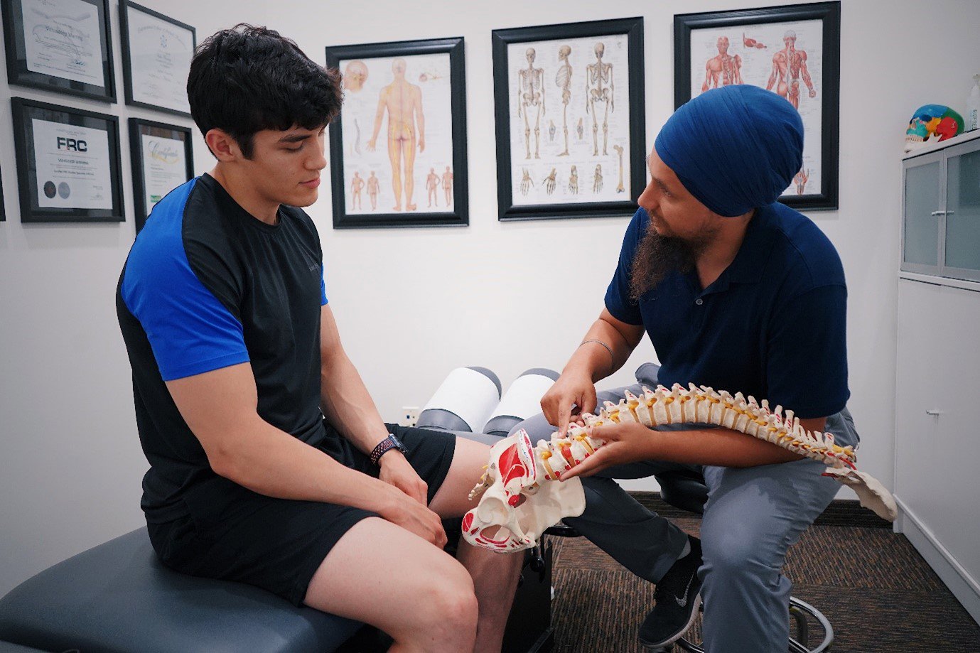 a medical professional and patient looking at a model spine