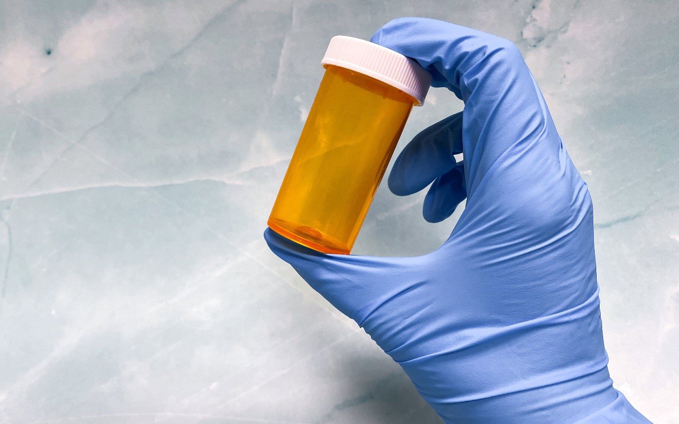 a gloved hand holding a bottle for medication