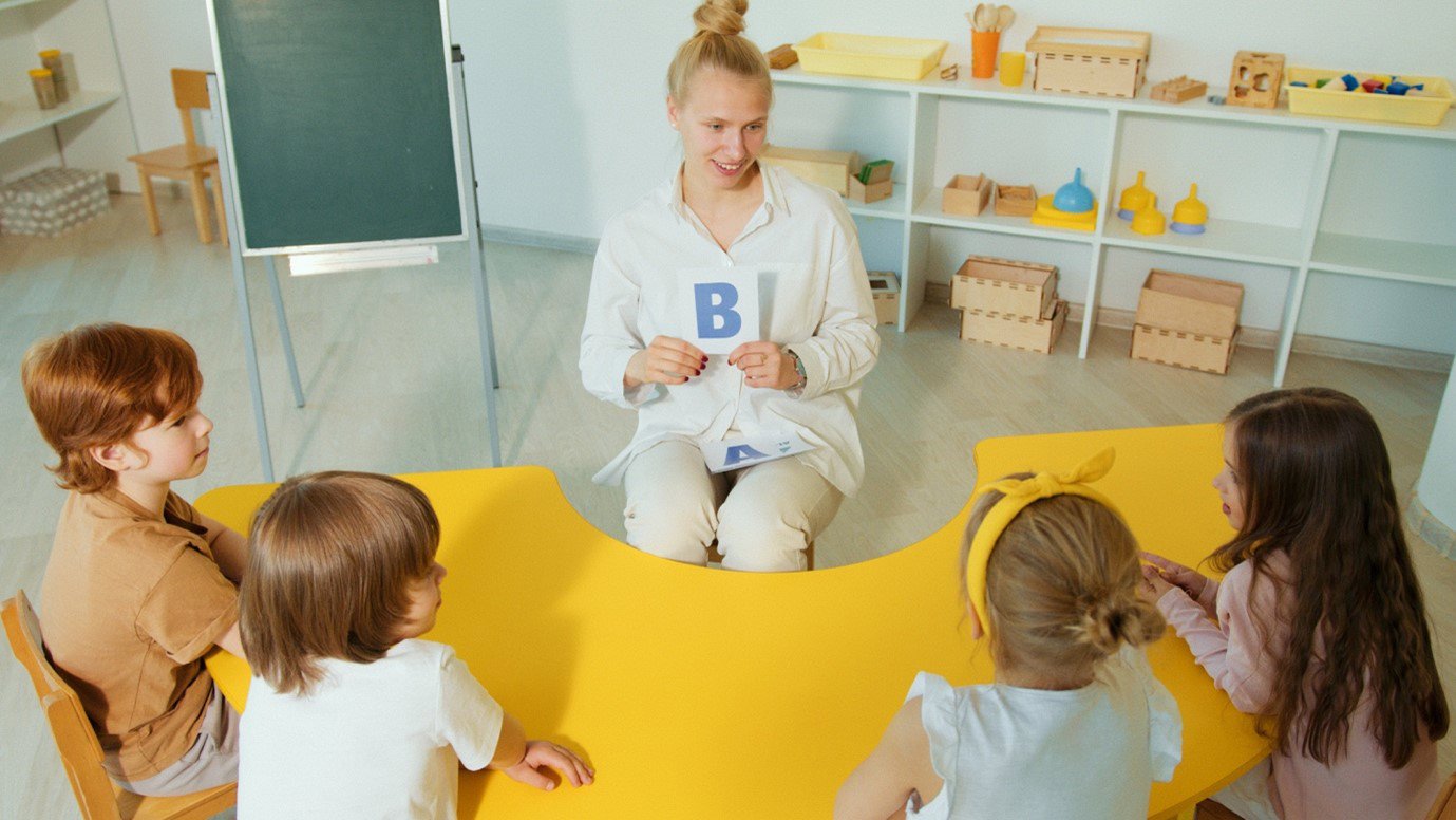 SEND teacher holding alphabet card