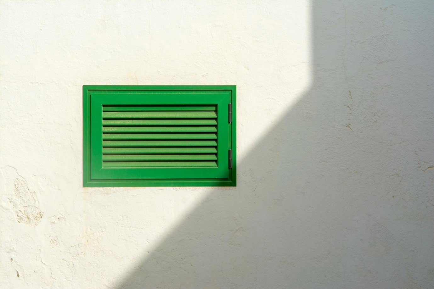 A green air vent on a wall
