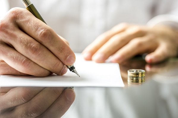 signing a document with wedding rings on the table