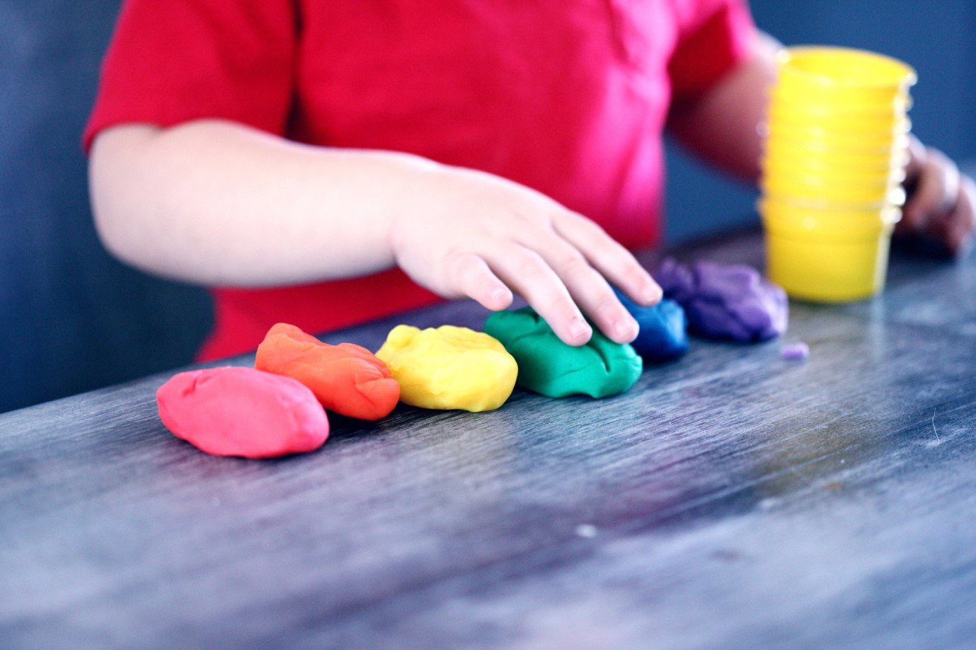 a child playing with different colours of playdoh