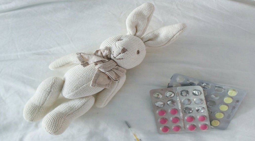 a toy rabbit on a bed with tablets and a syringe