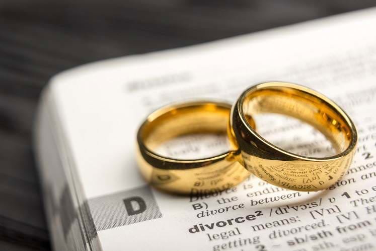 wedding rings on a dictionary, opened to the word 'divorce'