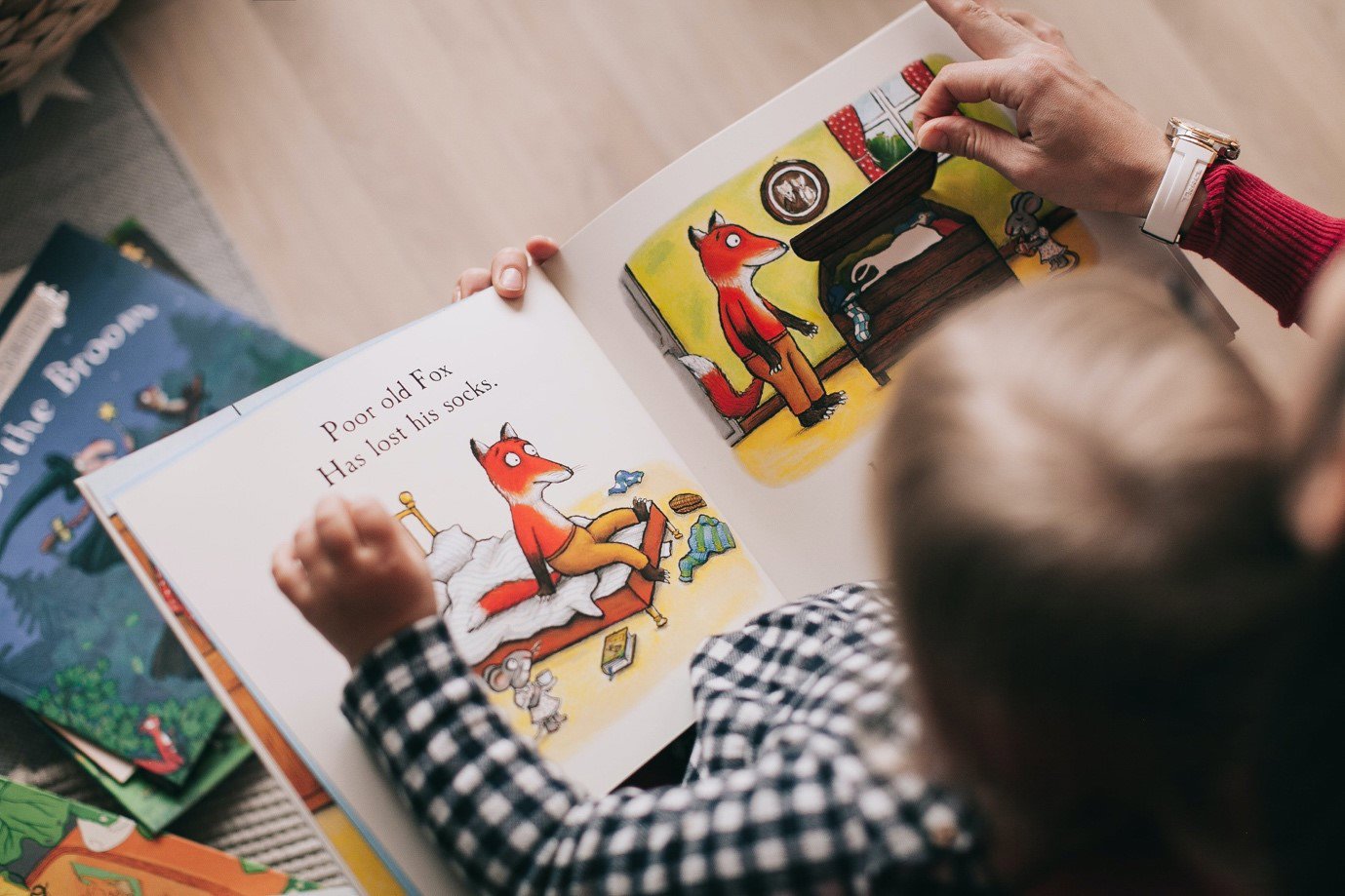 a young child reading a book with their parent