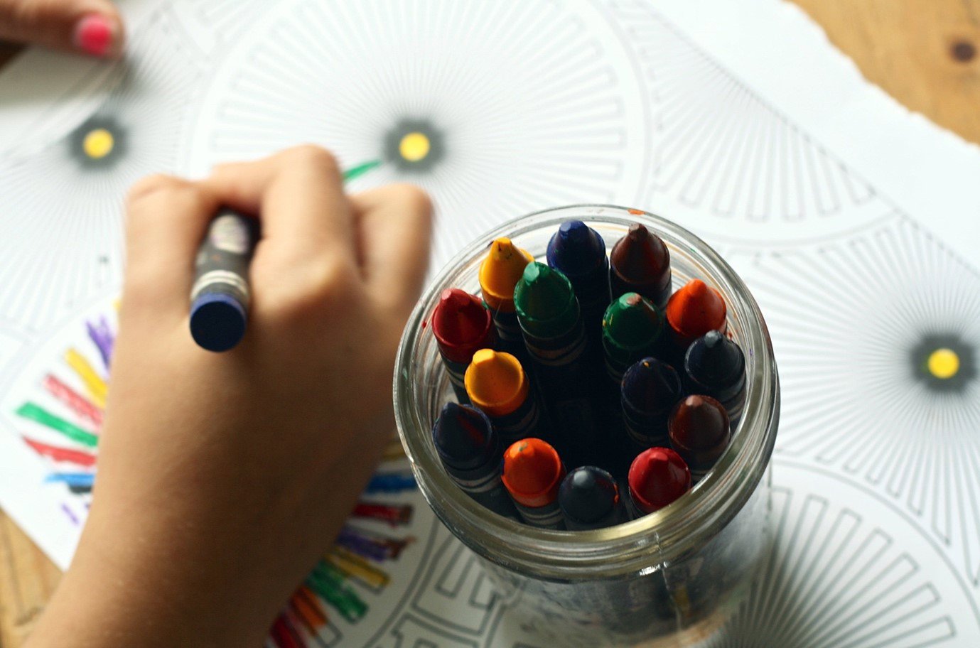 A child with a tub of different coloured crayons