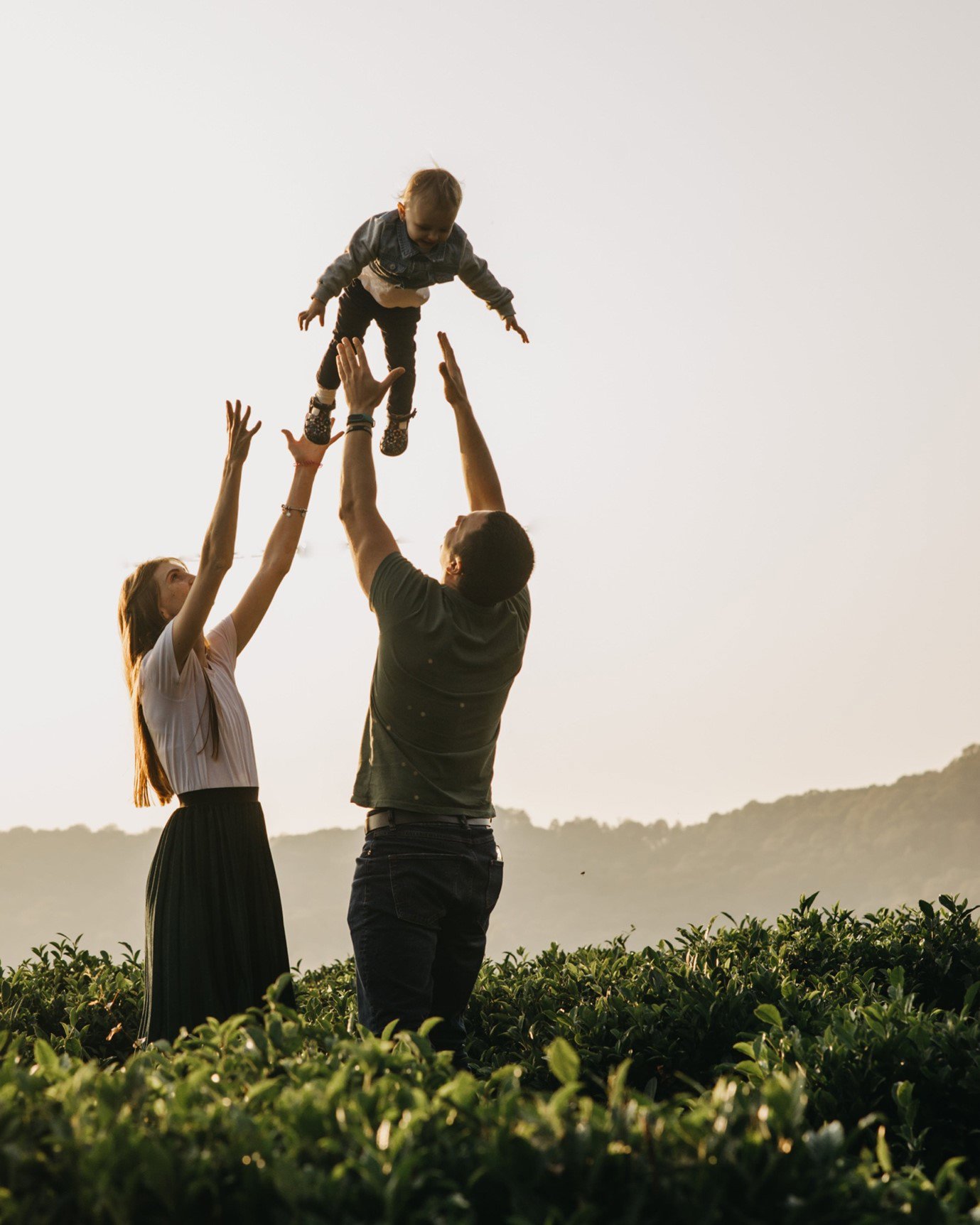 Family outside, parents are throwing their child in the air