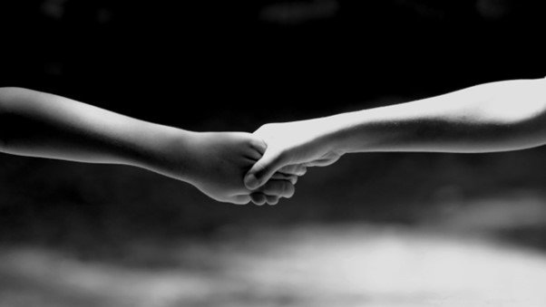 a black and white photo of two people holding hands