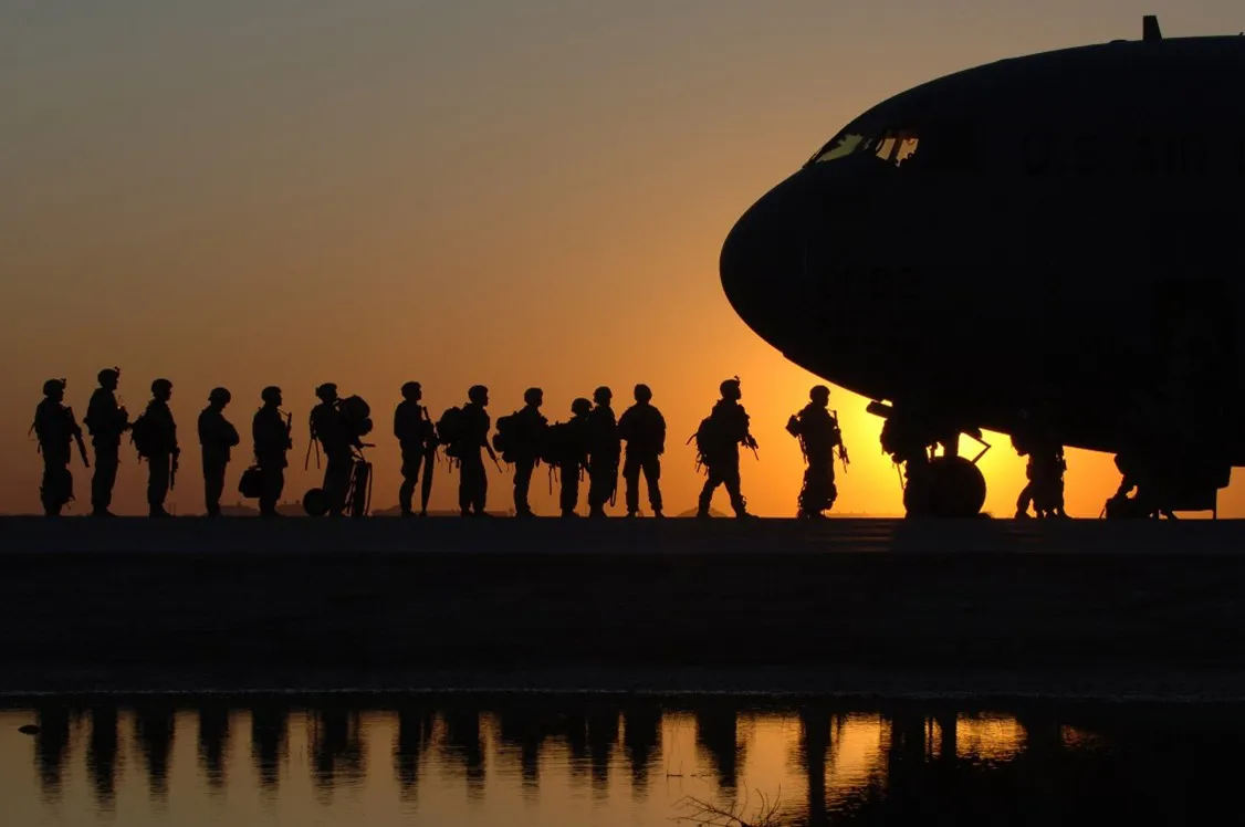 wide shot of soldiers' silhouettes walking to plane