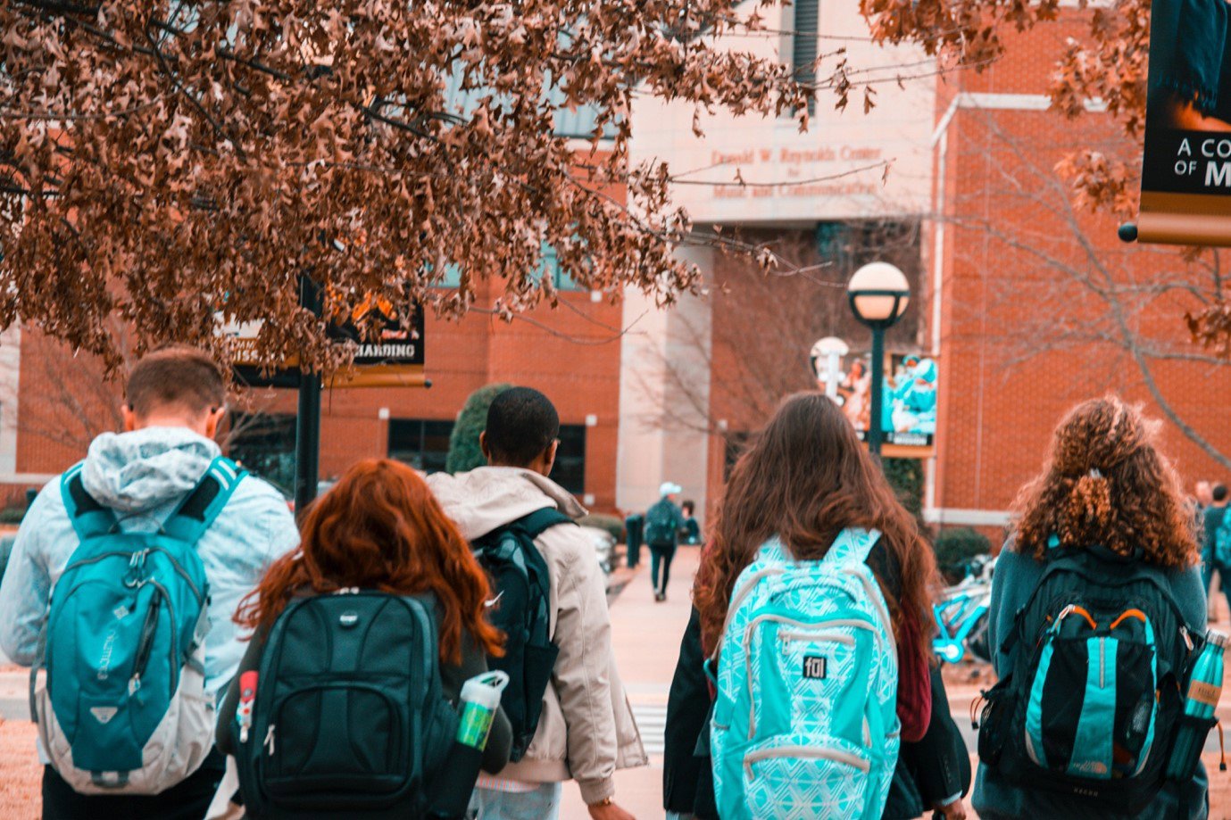 Children with backpacks walking outside a school