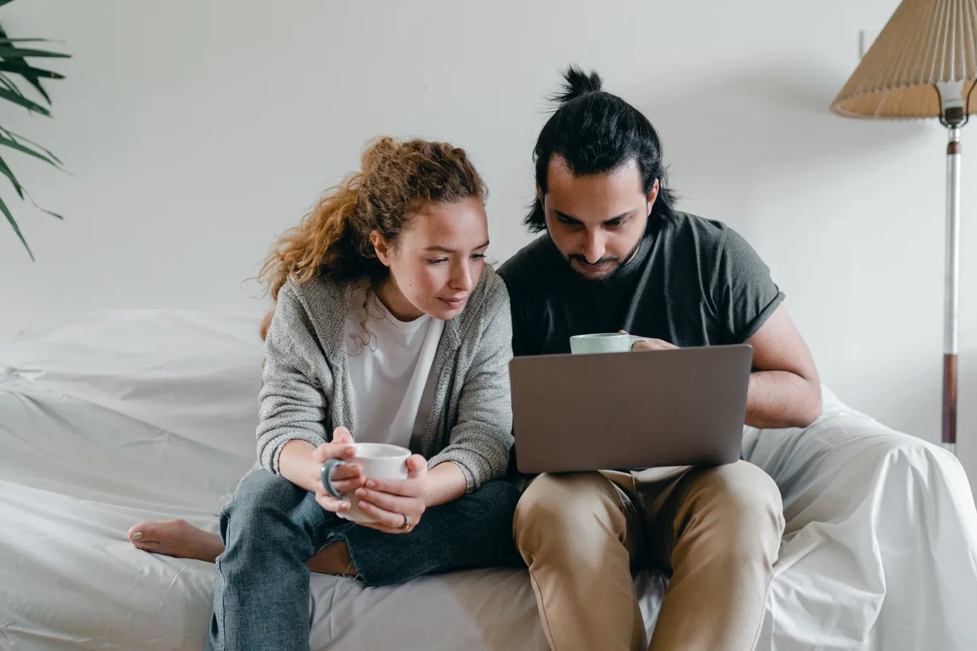 Couple sat on a bed looking at a laptop